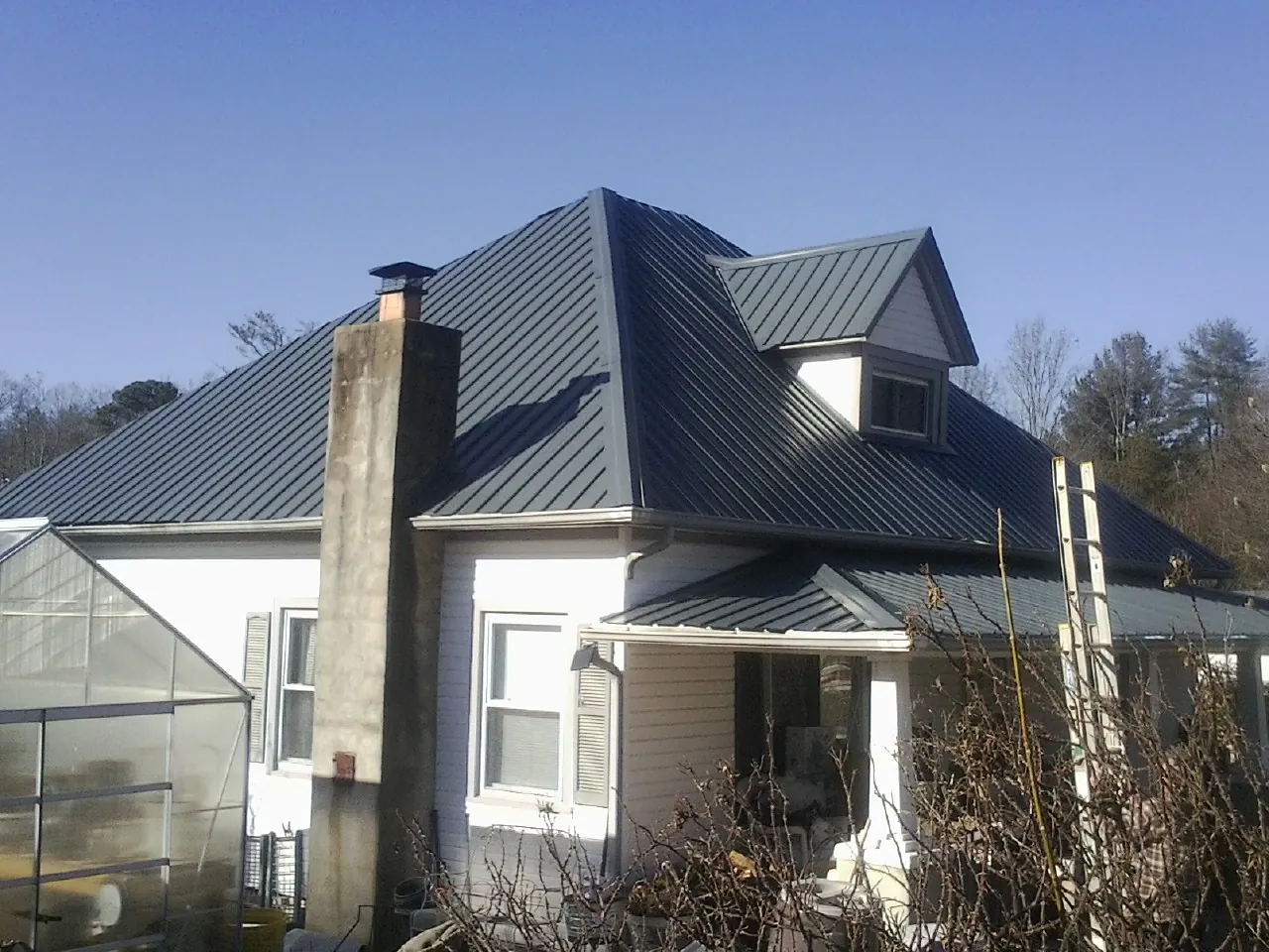 Dark blue standing seam metal roof on a white farmhouse with dormer — Slate & Tile Roof Repair by Roofing Brothers in Thurman