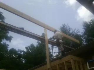 Carpenter setting a ridge beam over a new addition frame — Ice Dam Removal by Roofing Brothers in Thurman