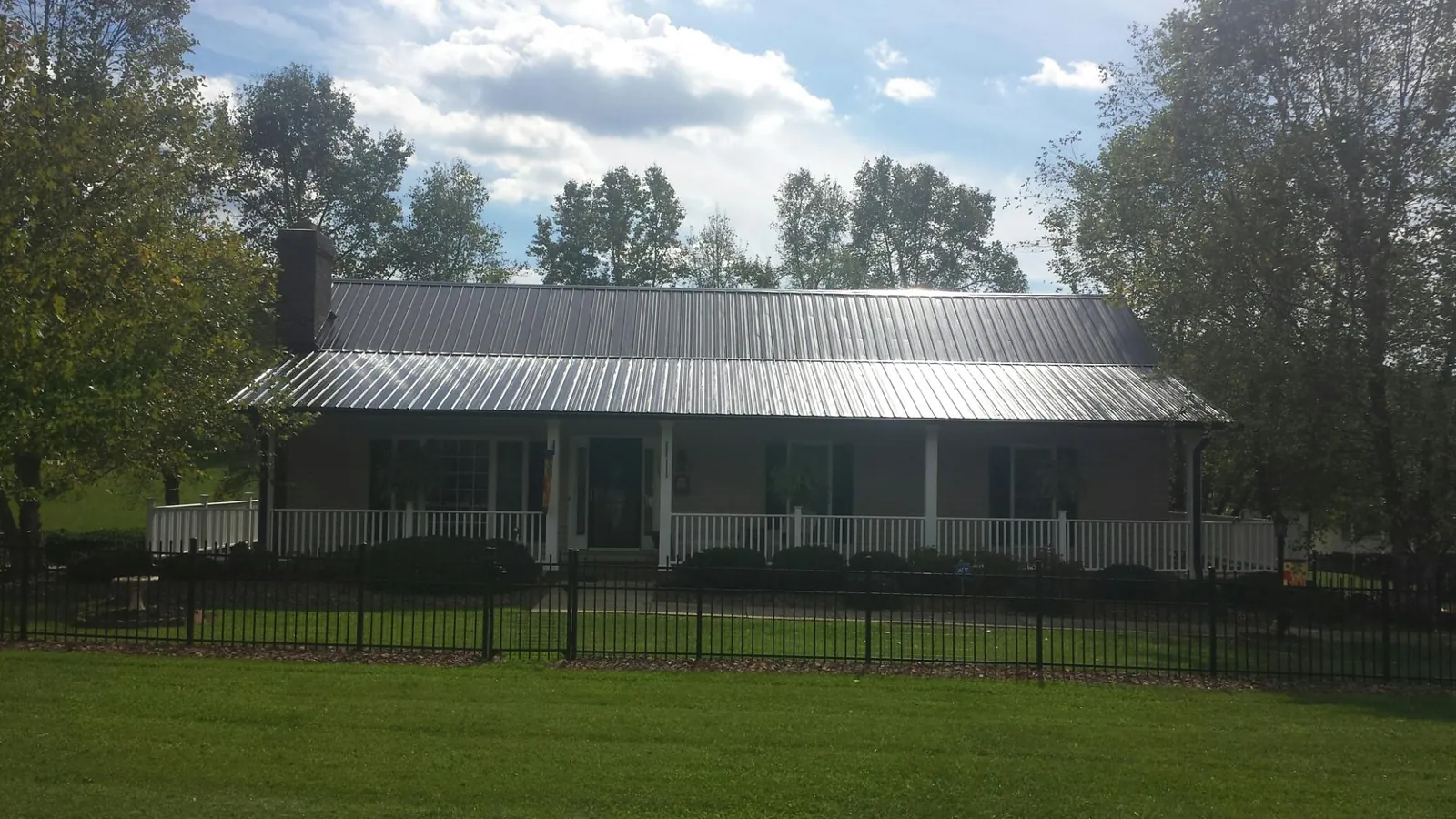 Gray metal roof on a brick ranch with a full width front porch — Gutter Guard Installation work by our crew in Thurman