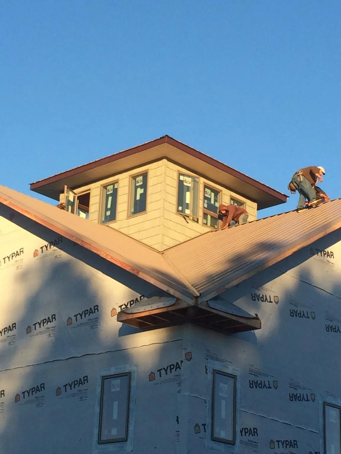 Roofers working around a rooftop cupola on a new metal roof at sunset — Roof Waterproofing in Thurman by Roofing Brothers